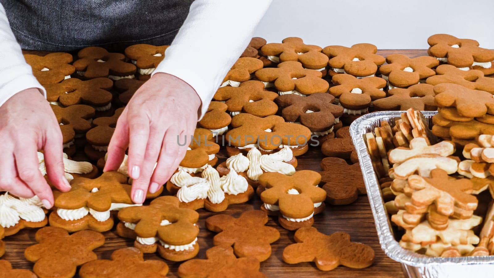 Crafting gingerbread cookie sandwiches with eggnog buttercream, presented on a rustic wooden table for Christmas gifting.