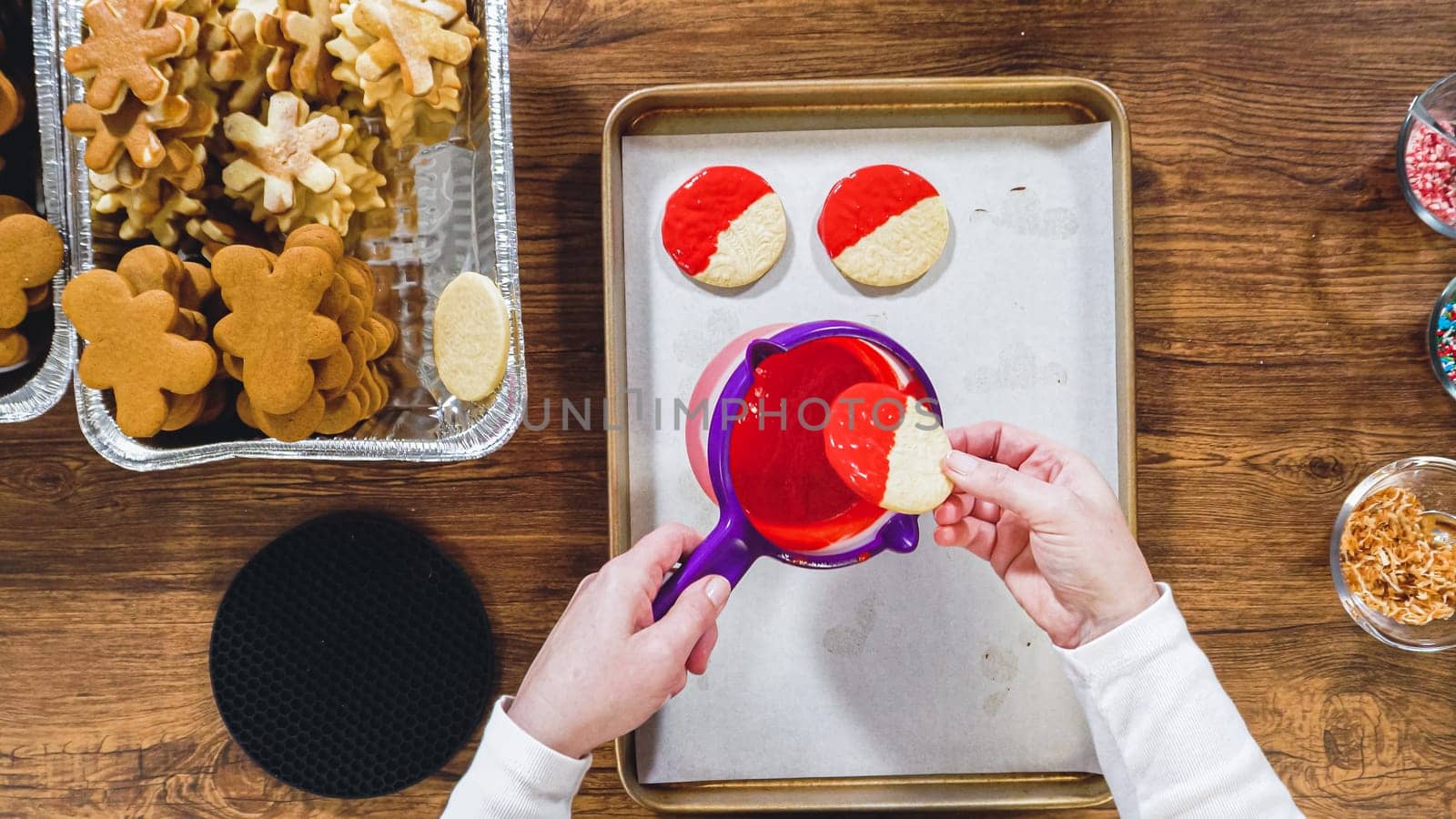 Flat lay. Creating snowflake-shaped cutout sugar cookies, dipped in chocolate, and adorned with different toppings.