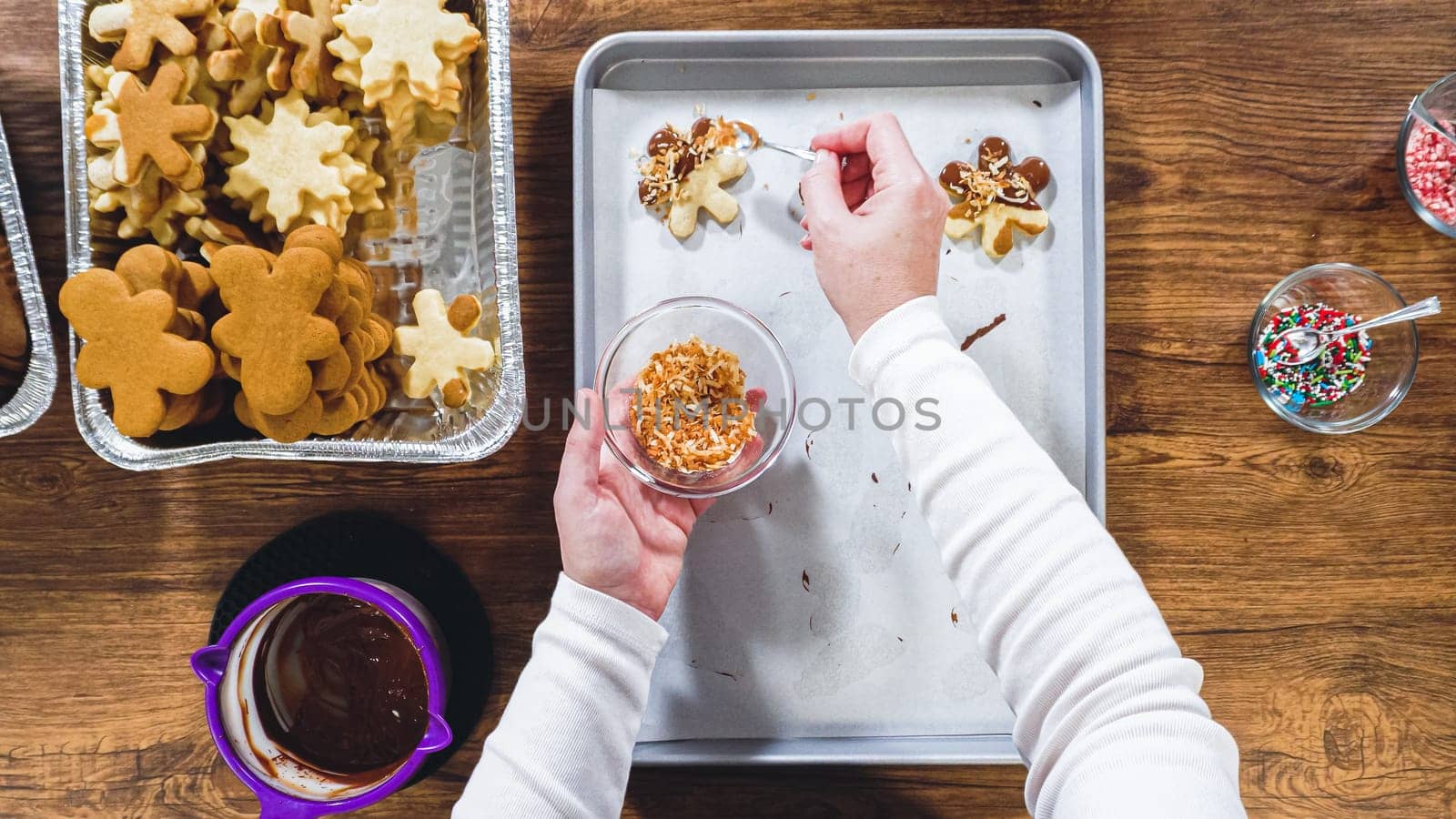 Flat lay. Creating snowflake-shaped cutout sugar cookies, dipped in chocolate, and adorned with different toppings.