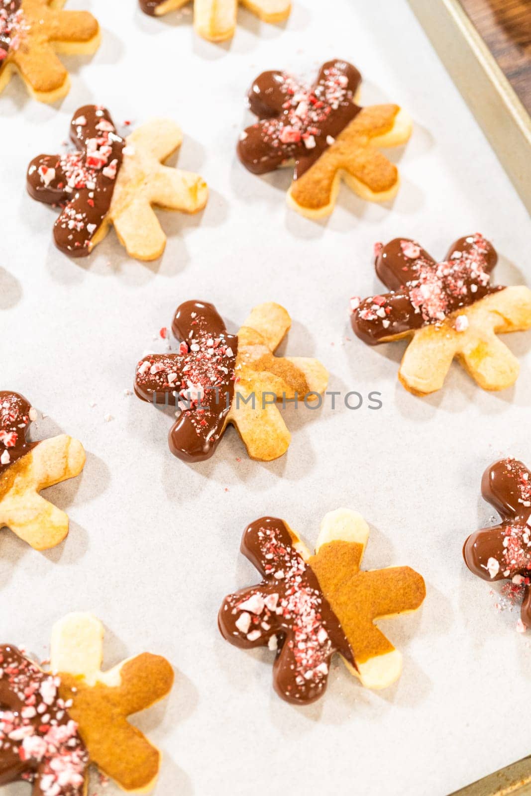 Preparing star-shaped cookies, half-dipped in chocolate, accented with peppermint chocolate chips for the holidays.