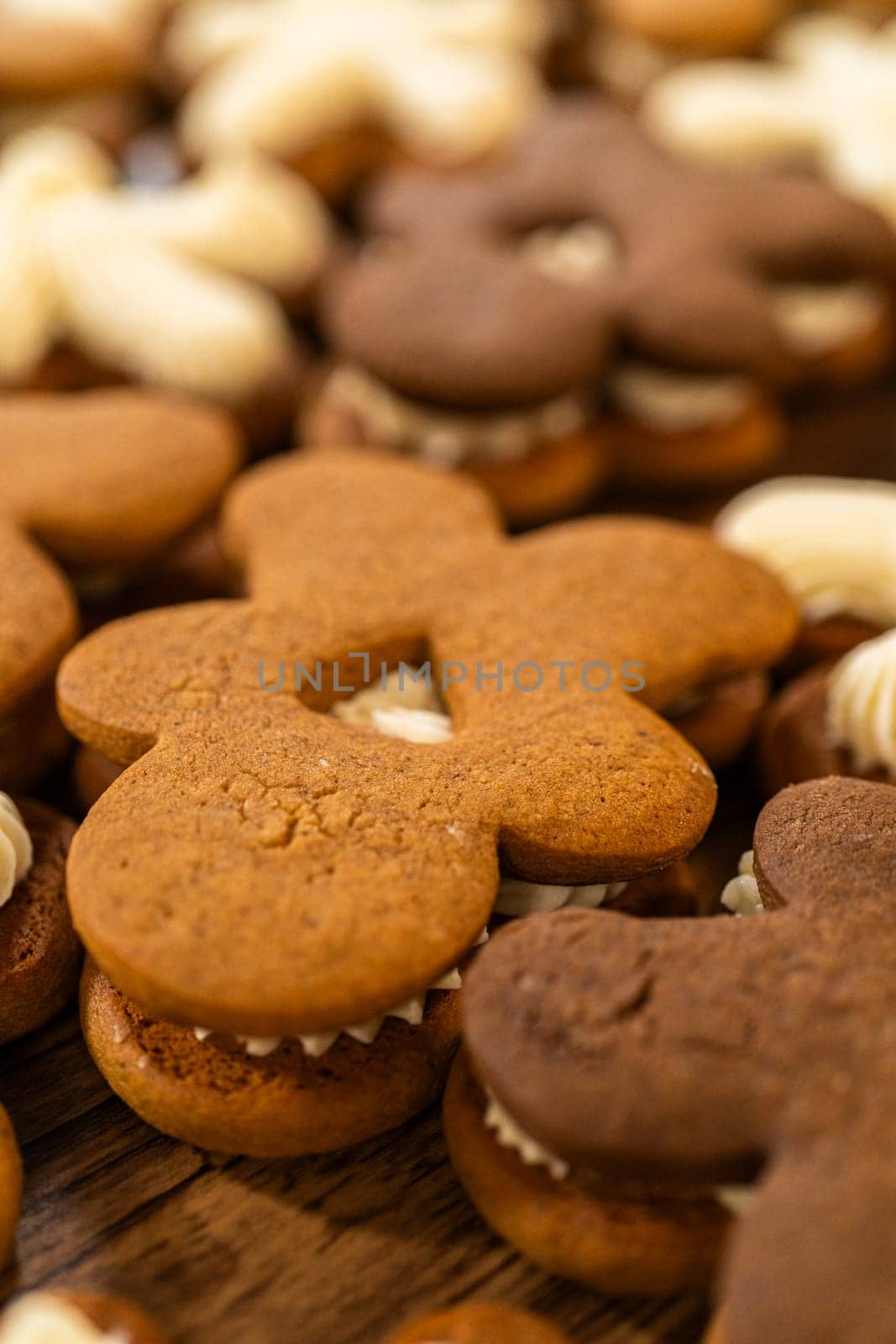 Making gingerbread man cookie sandwiches filled with eggnog buttercream, arrayed on a rustic wooden table, ideal for heartfelt Christmas gifting.