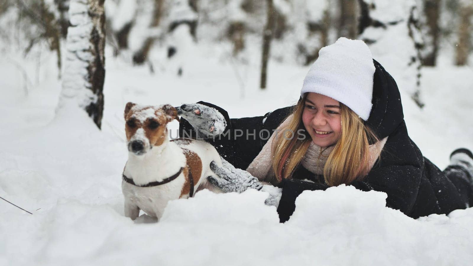 A girl playing with her Jack Russell Terrier dog in the snow. by DovidPro