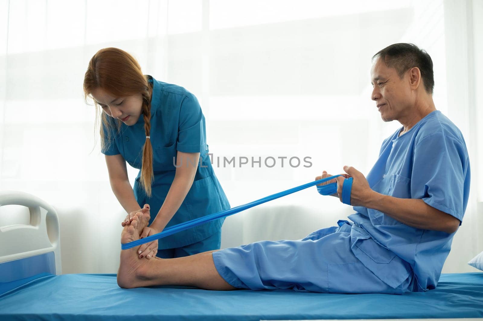 A sick caregiver or young nurse is helping a patient who is rehabilitating with physical therapy at the hospital. by wichayada