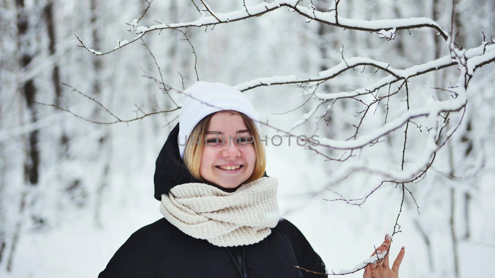 A girl gently touches snowy tree branches in the forest. by DovidPro