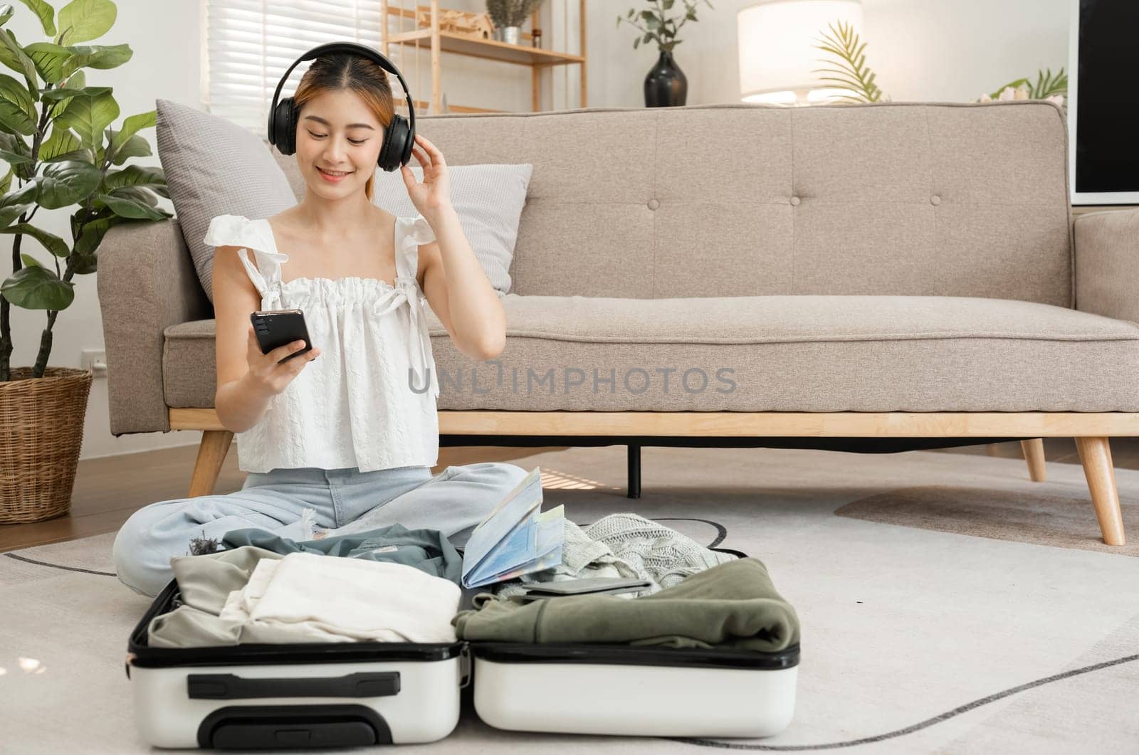 beautiful young woman happy Wear headphones to listen to music while packing your suitcase..