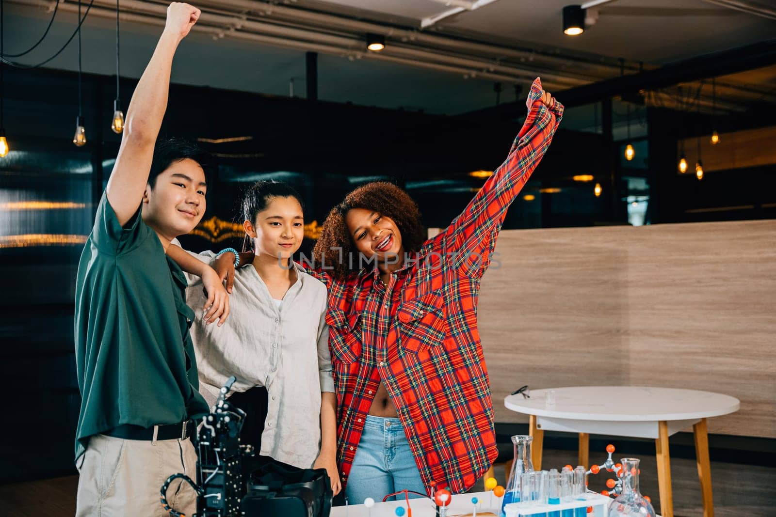 In classroom environment jubilant group of students raises hands celebrating their accomplishment after fascinating robotics class exploring futuristic robotic arm in Innovation and Technology studies