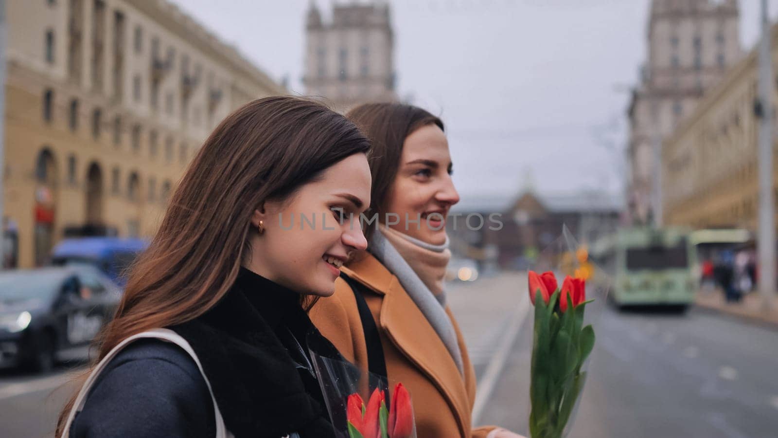 two beautiful young women walking together along a city street in spring