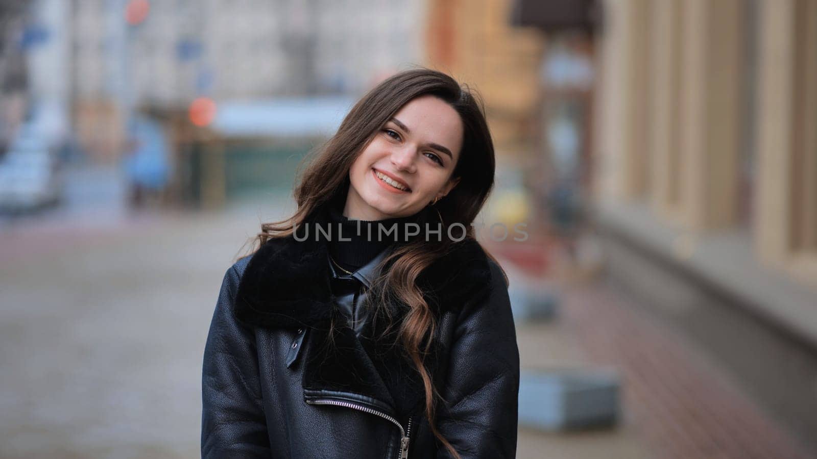 Happy brunette girl posing in black jacket in autumn in the city