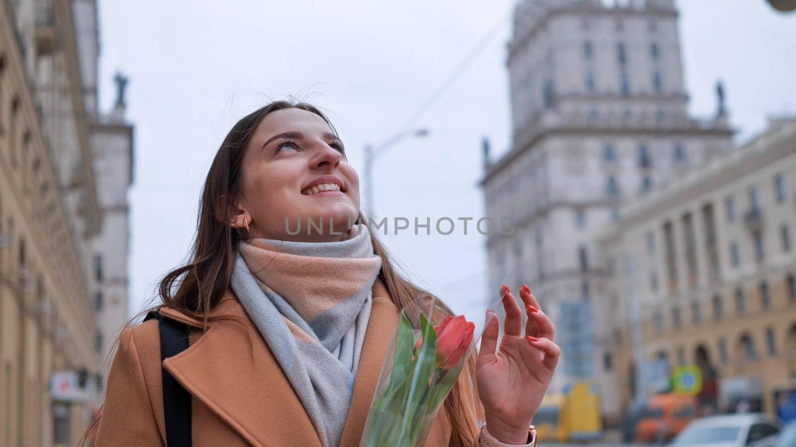 Portrait of a happy shade girl with a tulip in the background of the city in the cold season