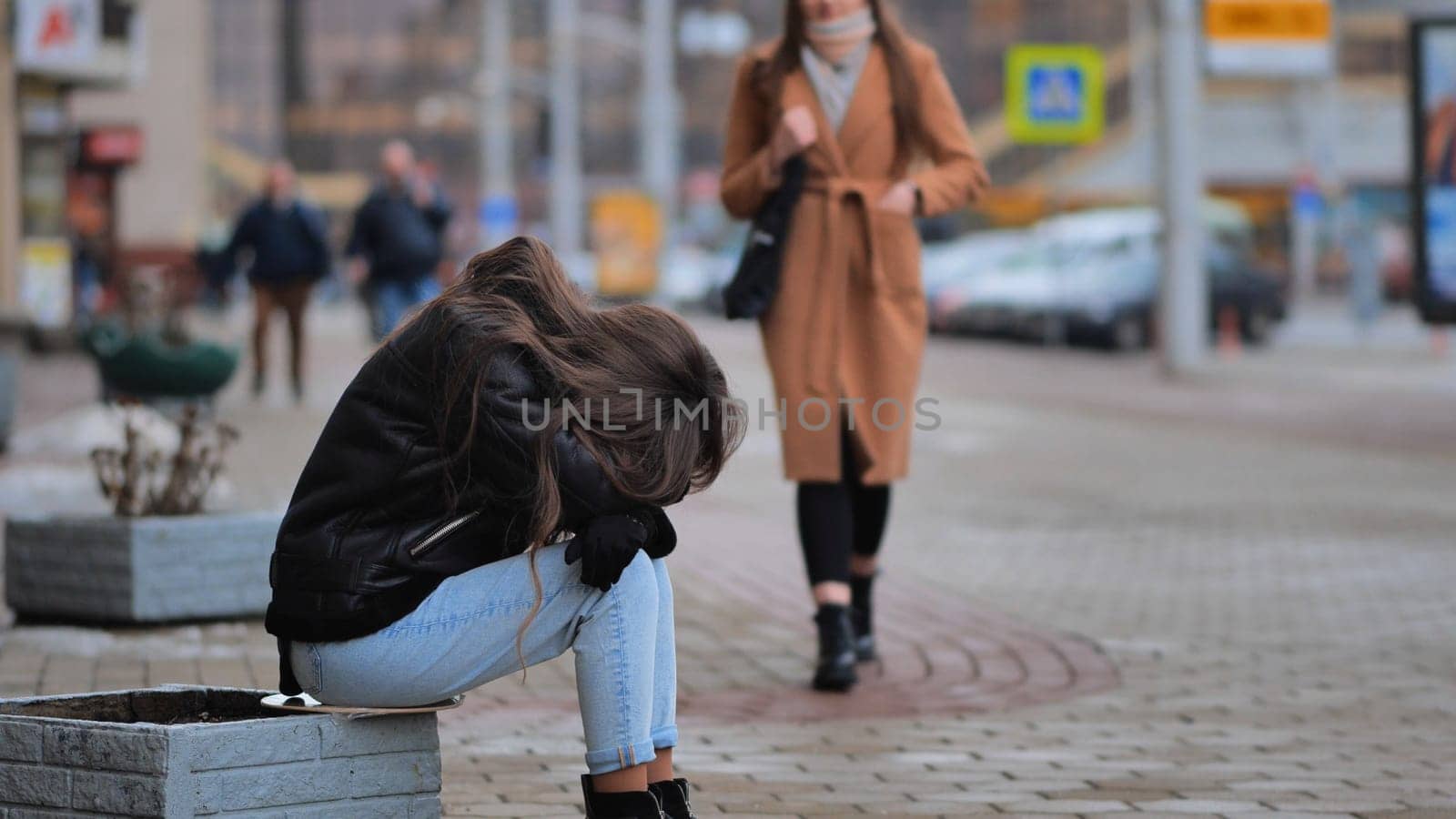 A girl crying sitting on a flowerbed in the city