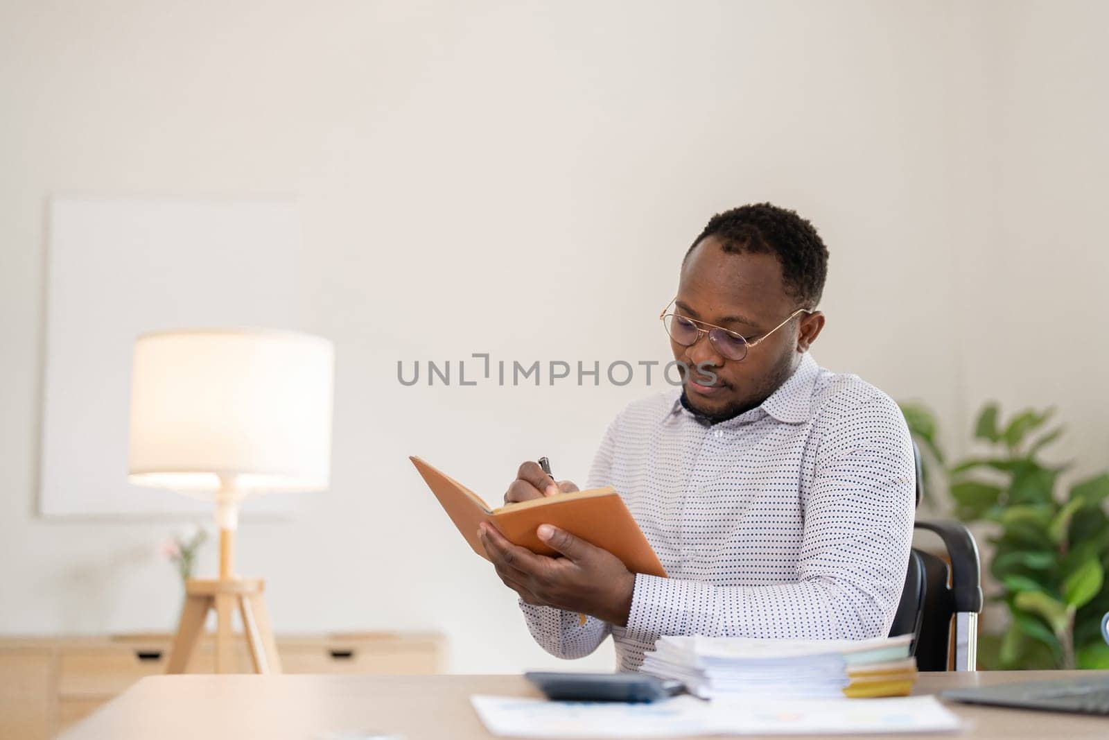 African American businessman working with documents, taking notes in the office, preparing a performance analysis report..