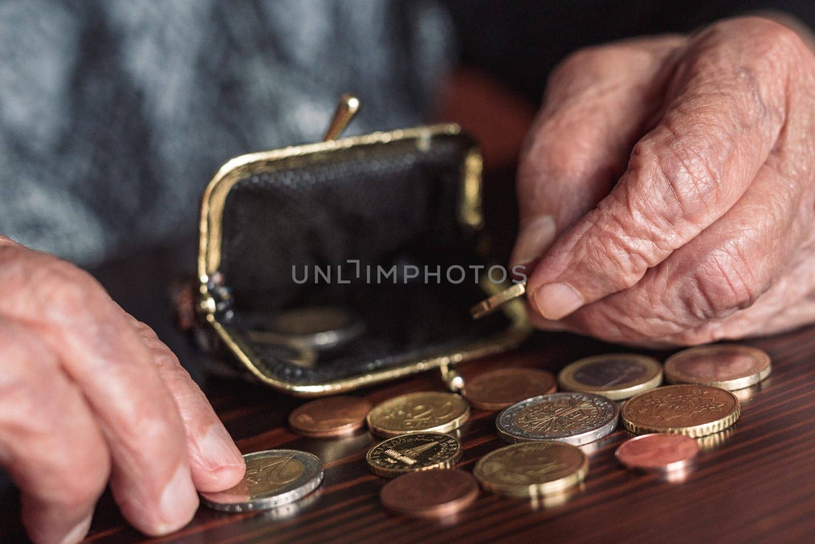 Detailed closeup photo of elderly 96 years old womans hands counting remaining coins from pension in her wallet after paying bills. Unsustainability of social transfers and pension system. by kasto