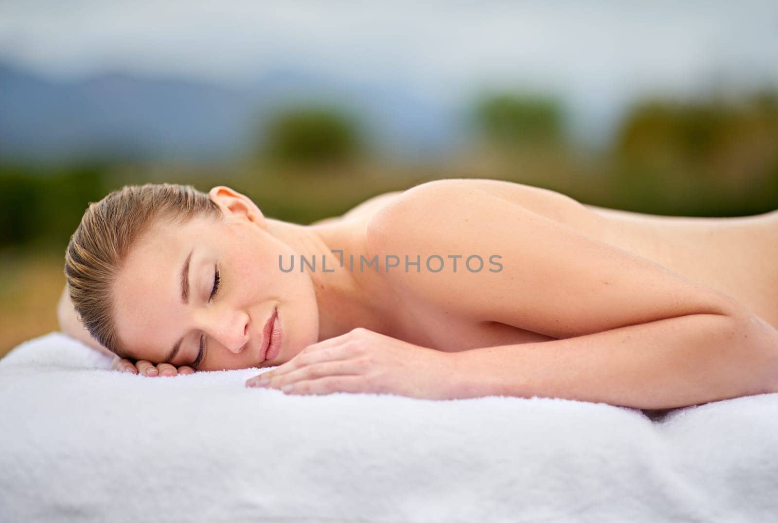 Woman, relax and massage table in spa, therapy and self care for body wellness and resting for tension. Comfortable and resort with client, stress free and healing, calm session and cosmetology by YuriArcurs