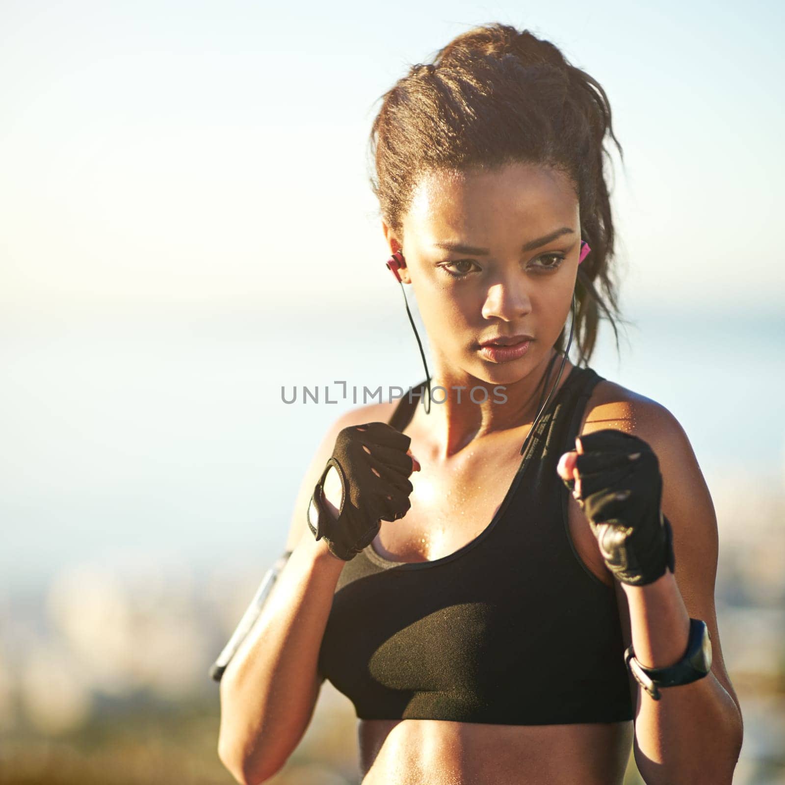 Woman, boxer and fists for outdoor exercise with earphones or streaming music, podcast or subscription. Female person, fighter and athlete for fitness routine in nature park or playlist, audio or fit.