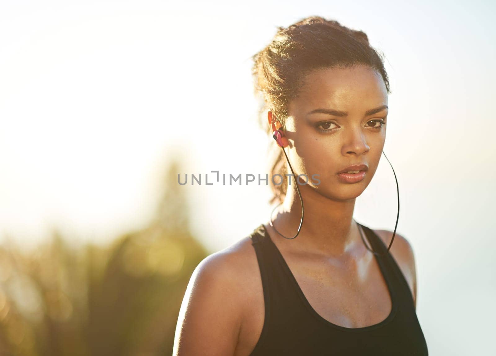 Woman, portrait and outdoor fitness with earphones for streaming music, subscription or training. Female person, face and athlete podcast or playlist audio for running performance, cardio or sunset.