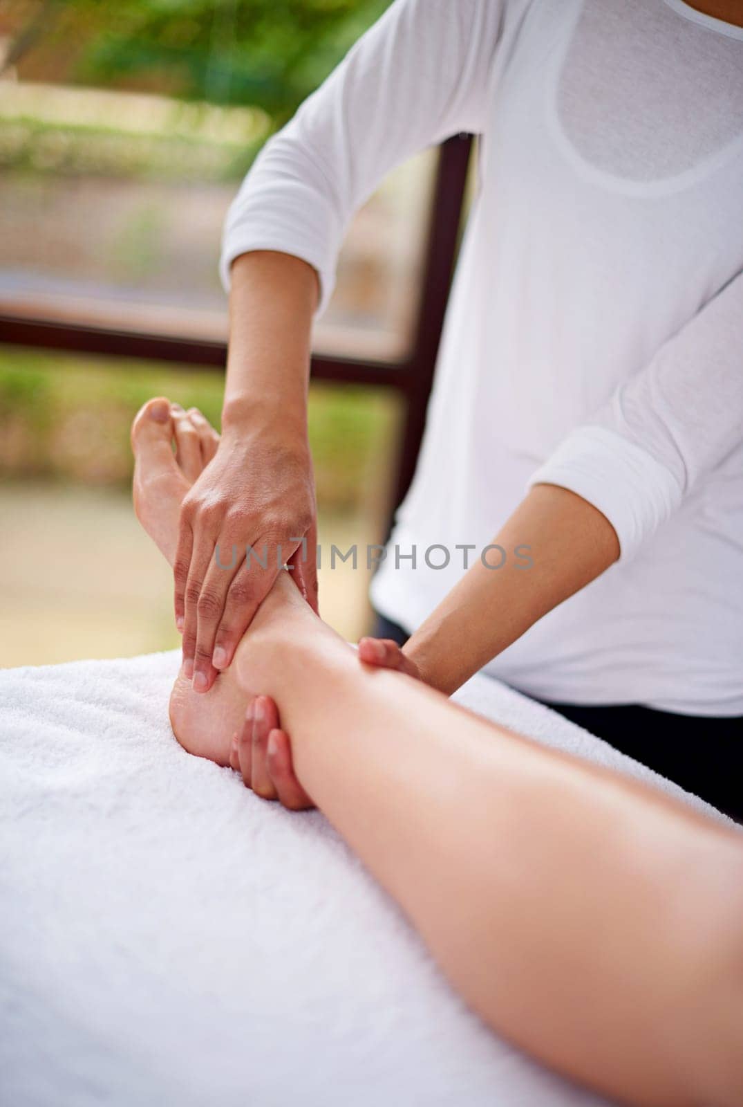 Woman, foot and massage table in spa, therapy and self care for body wellness and resting for tension. Comfortable and resort with client, stress free and healing, calm session and cosmetology.