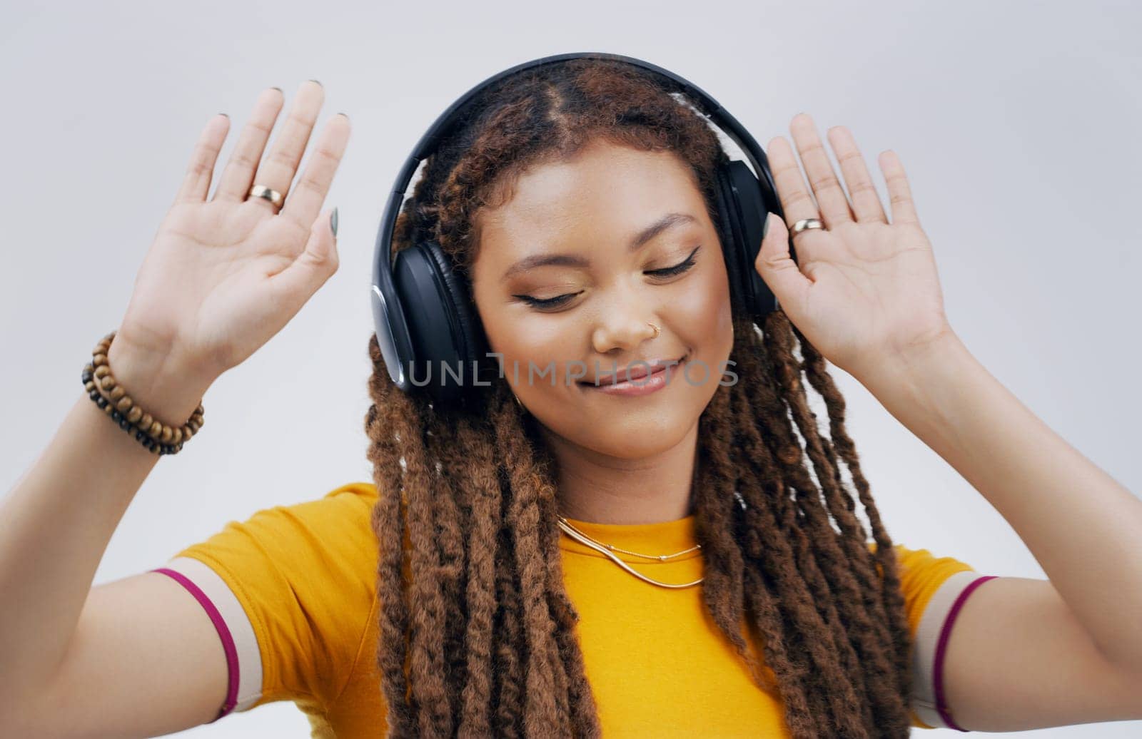 Woman, studio or celebrate with headphones in closeup for music, streaming or listening with happiness. Female student and dancing on backdrop with audio and hands, happy for podcast or radio by YuriArcurs