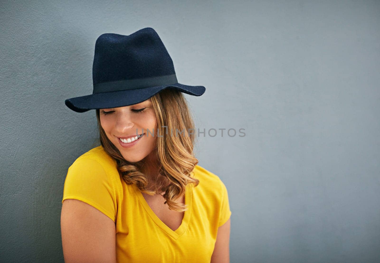 Woman, smile and hat by gray background with fashion inspiration, clothes and mockup for marketing. Happy, confidence and face of gen z person by dark wall with advertising space, fedora and style by YuriArcurs