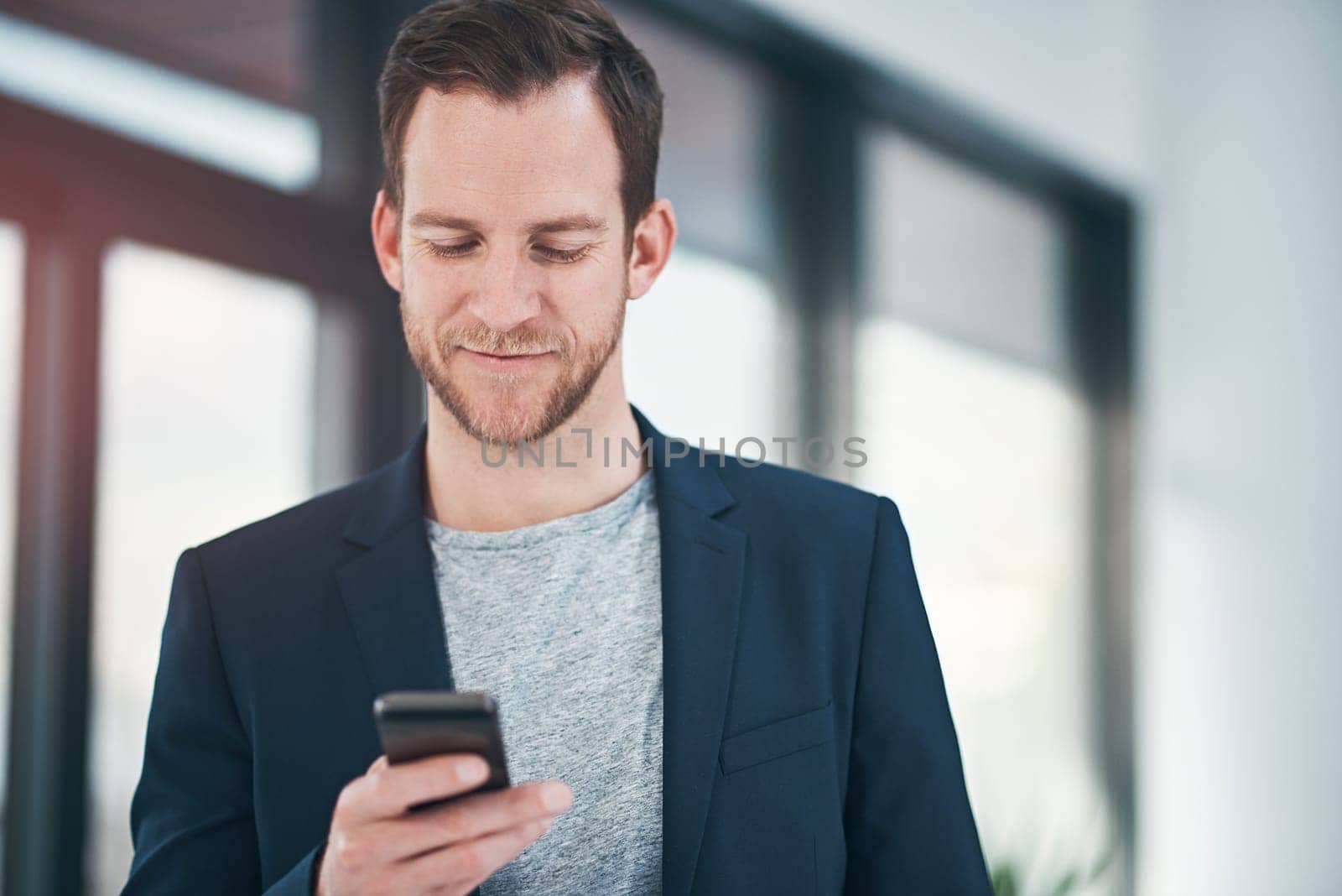 Happy, businessman and reading news with phone in research, review or online interaction at office. Man or employee with smile on mobile smartphone for chatting, texting or communication at workplace.