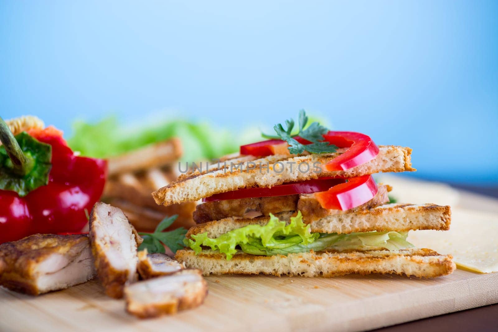 fried toast with chicken, salad, greens on a wooden table .