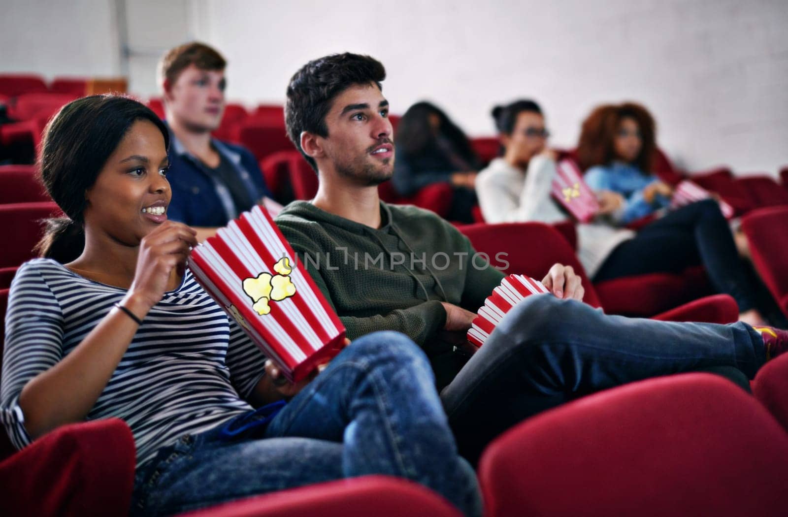 Movie, date and couple in cinema at night with popcorn to relax and watch in theatre with happiness. Film, experience and people in audience enjoy funny comedy, drama performance or eating snack food.