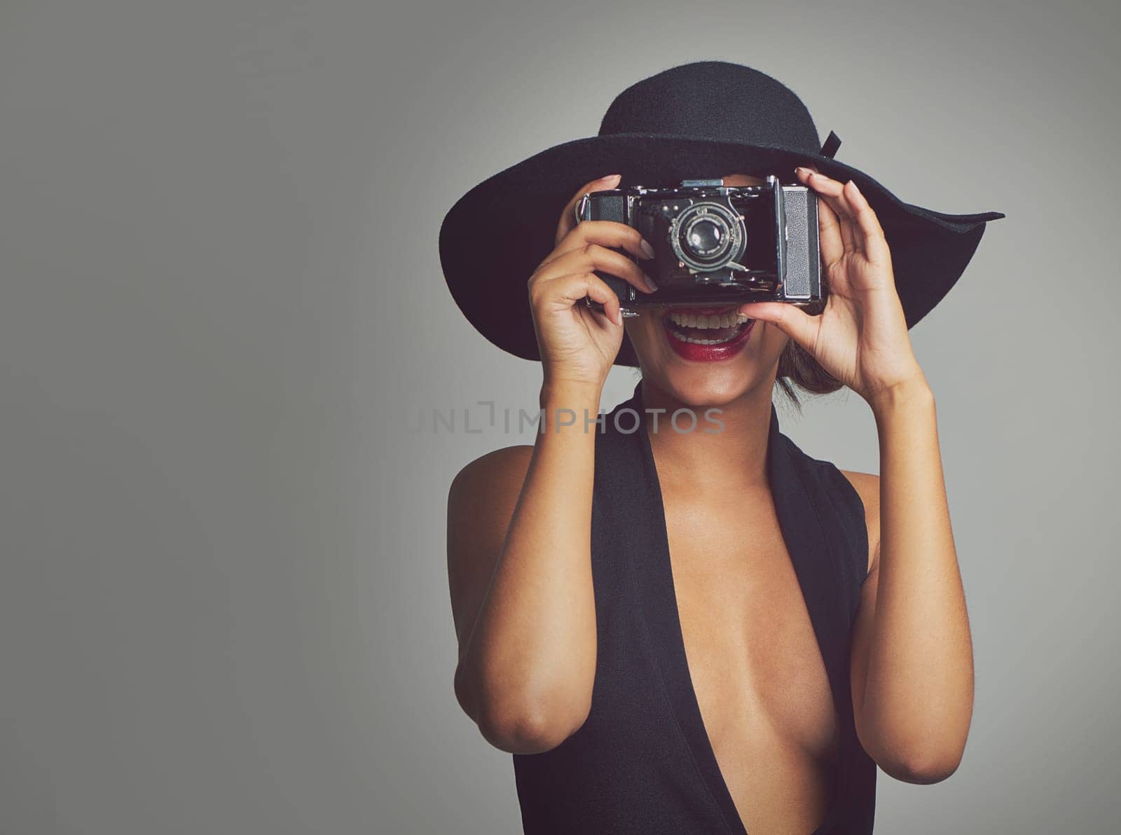Fashion, camera and elegant woman in hat, studio and smile isolated on gray background. Face, confident and style for summer outfit, classy aesthetic and clothes with glamour cosmetics in Brazil by YuriArcurs