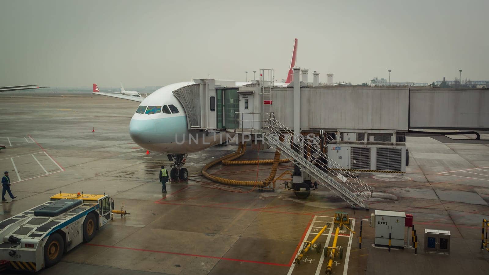 Shanghai, China - January 28, 2019: Airplane ready for boarding in Shanghai airport hub on rainy day by Busker