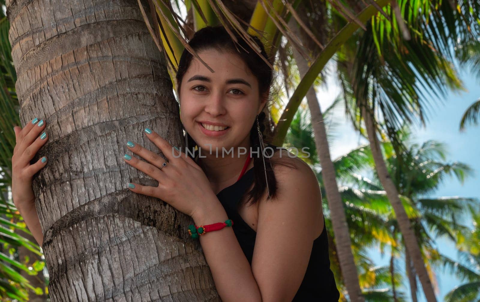 Close-up of cute asian girl hugging palm tree trunk, summer vacation, relaxation on the beach, Philippines by Busker
