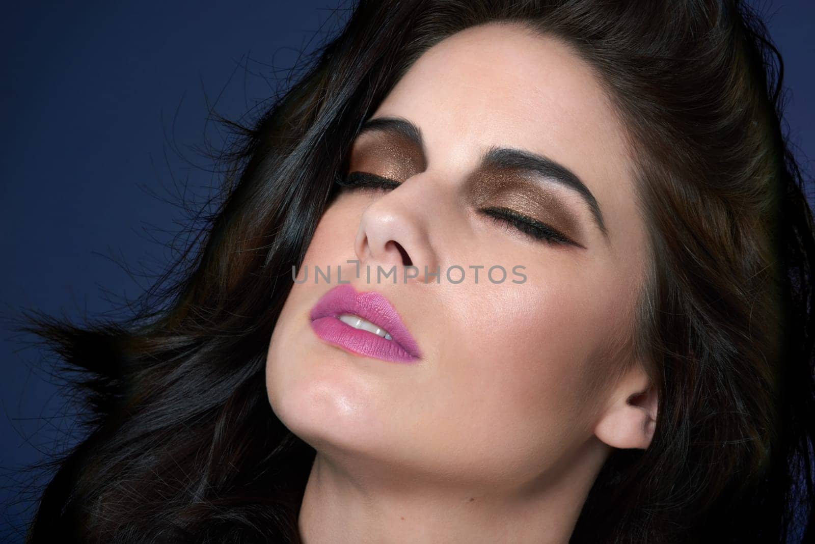 Beauty, woman and makeup with cosmetics, shine and dermatology on blue studio background. Person, girl and model with glow, wellness or luxury with treatment, grooming and healthy skin with aesthetic.