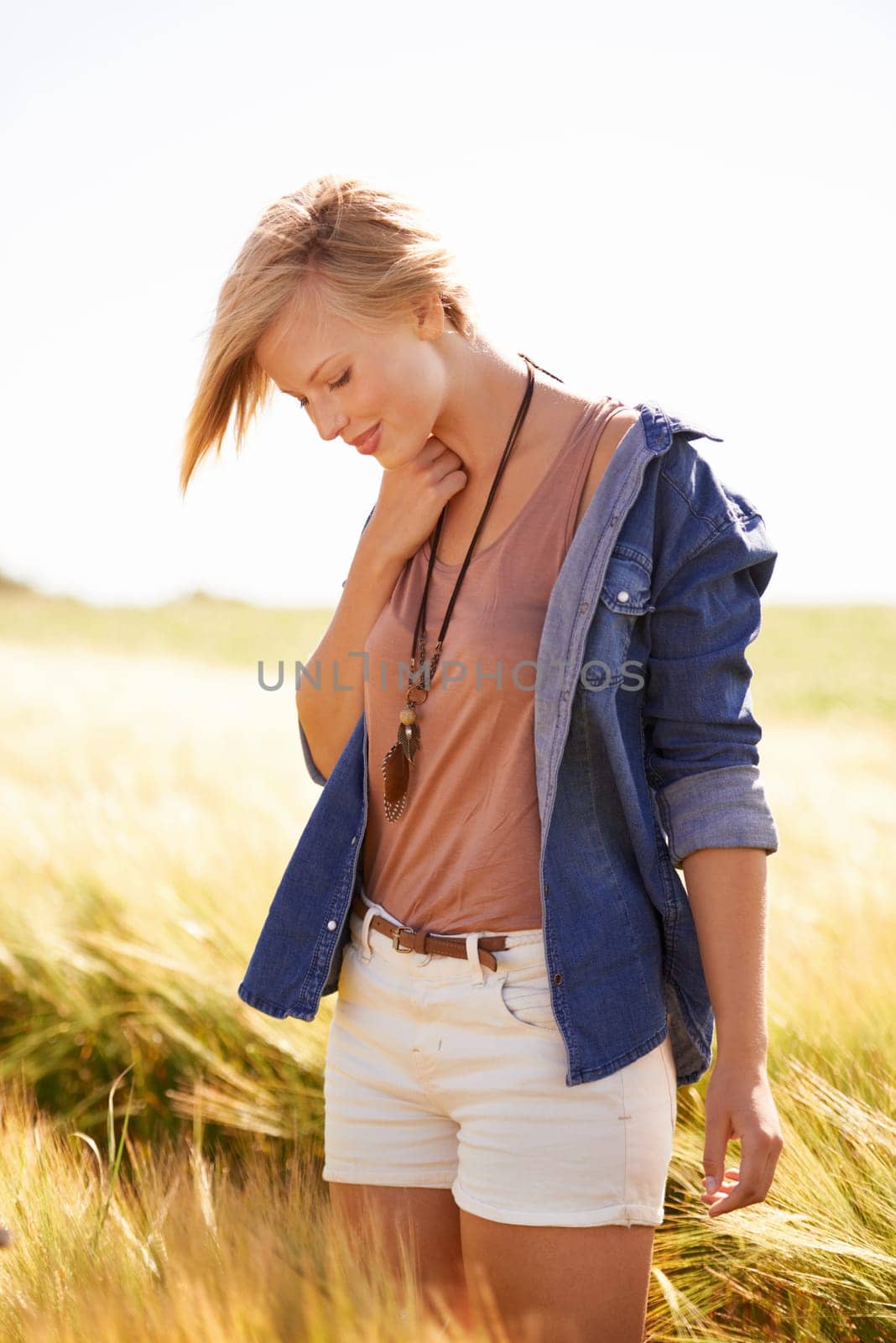 Woman, field and countryside with wind for holiday in New Zealand for summer, environment or outdoor. Female person, sunshine and fresh air in long grass for traveling adventure, vacation or nature by YuriArcurs