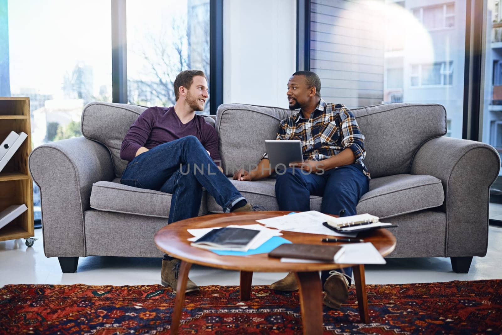 Business people, teamwork and meeting on sofa with tablet for collaboration and planning of creative software. Graphic designer, men or clients relax on couch in office with digital ideas and advice.