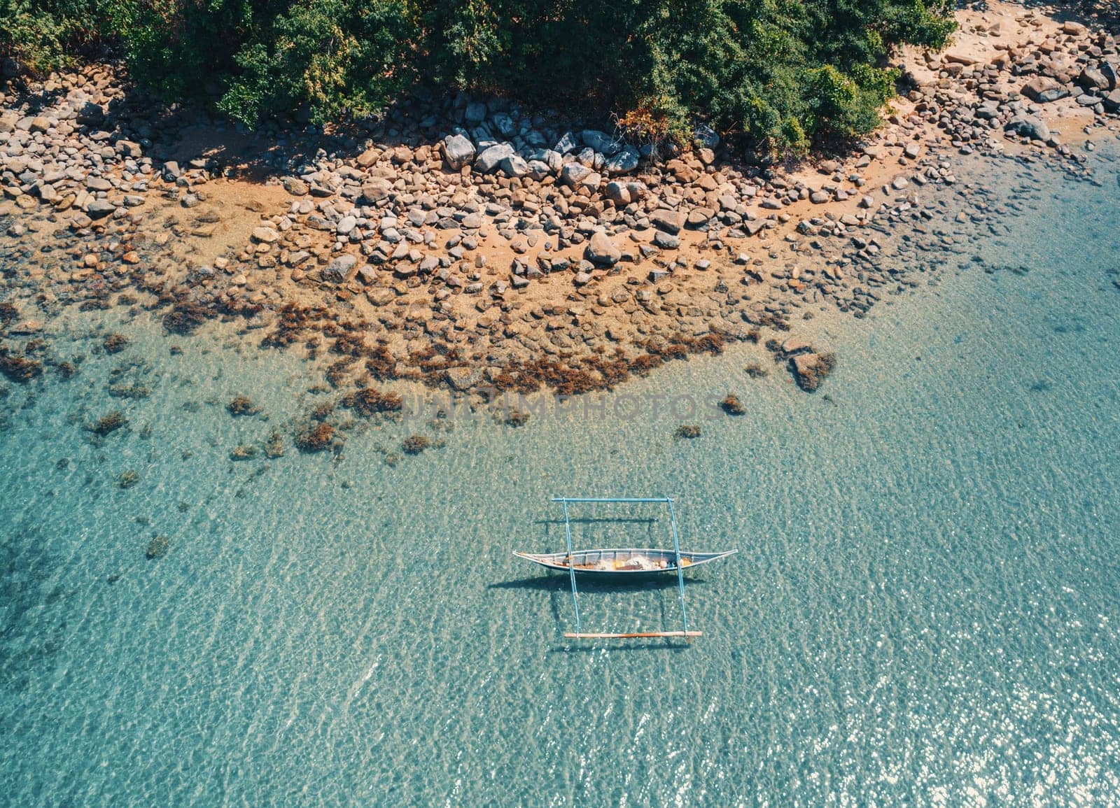 Aerial drone view of boat anchored in the bay with clear and turquoise water. Boat in the tropical lagoon. Tropical landscape.