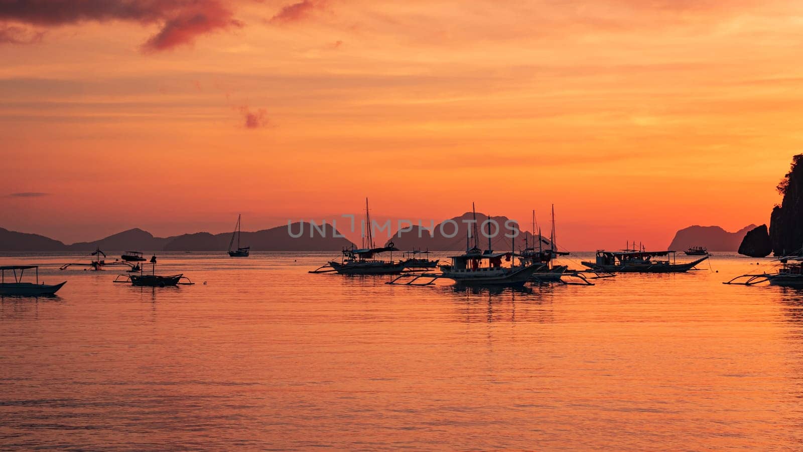 Traditional philippine boat bangka at sunset time. Beautiful sunset with silhouettes of philippine boats in El Nido, Palawan island, Philippines. by Busker