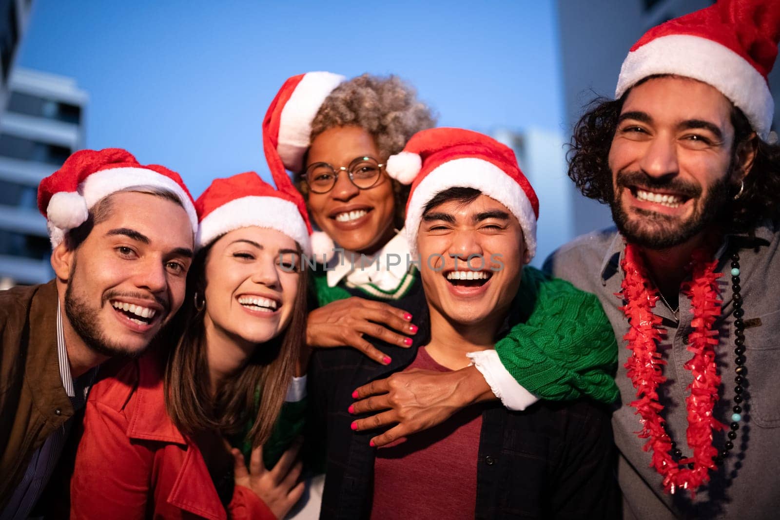 Group of smiling multiracial friends wearing Santa Claus hats looking at camera celebrate Christmas together. Friendship concept. Holidays concept.