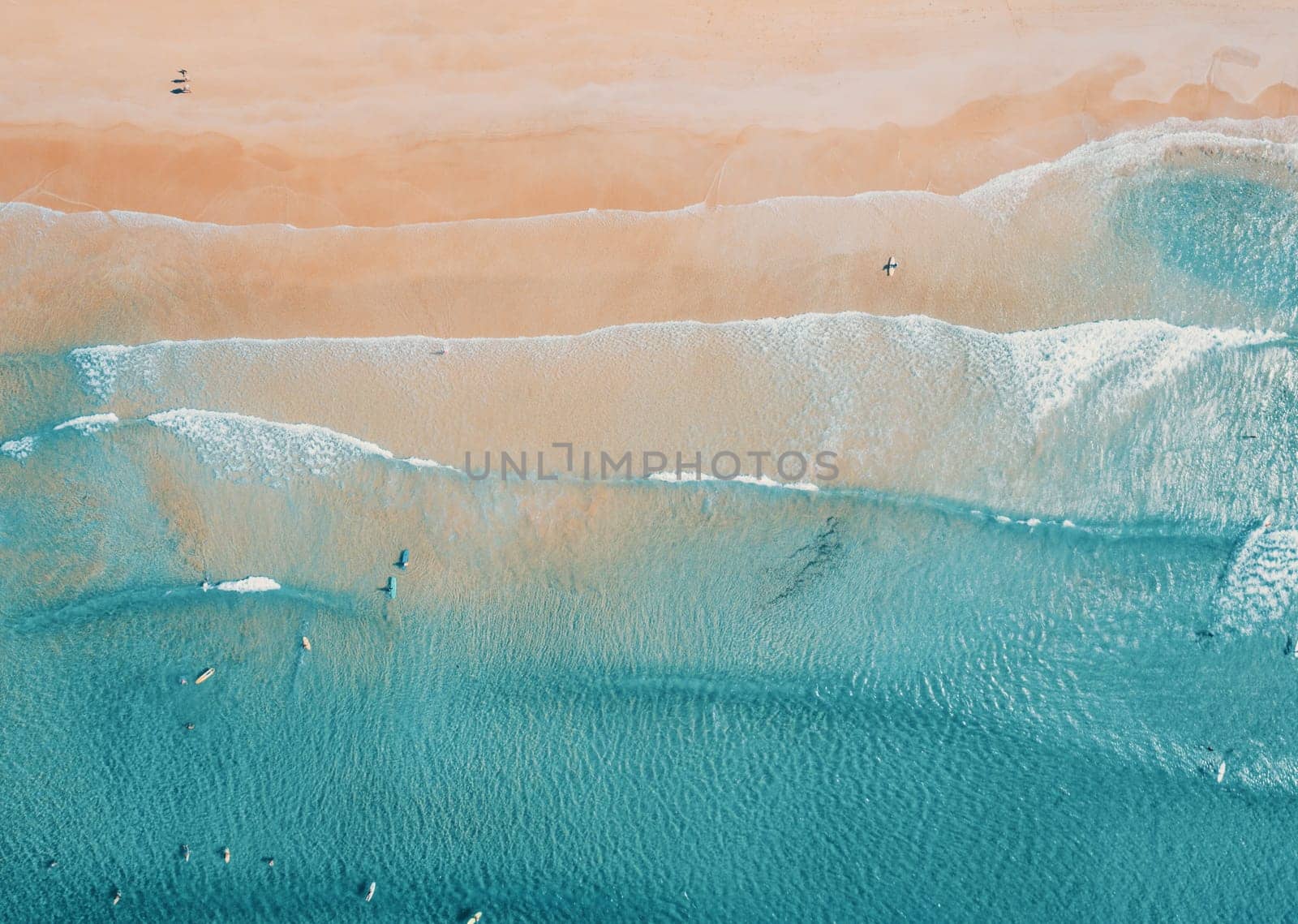 Aerial top view of turquoise ocean wave reaching the coastline.