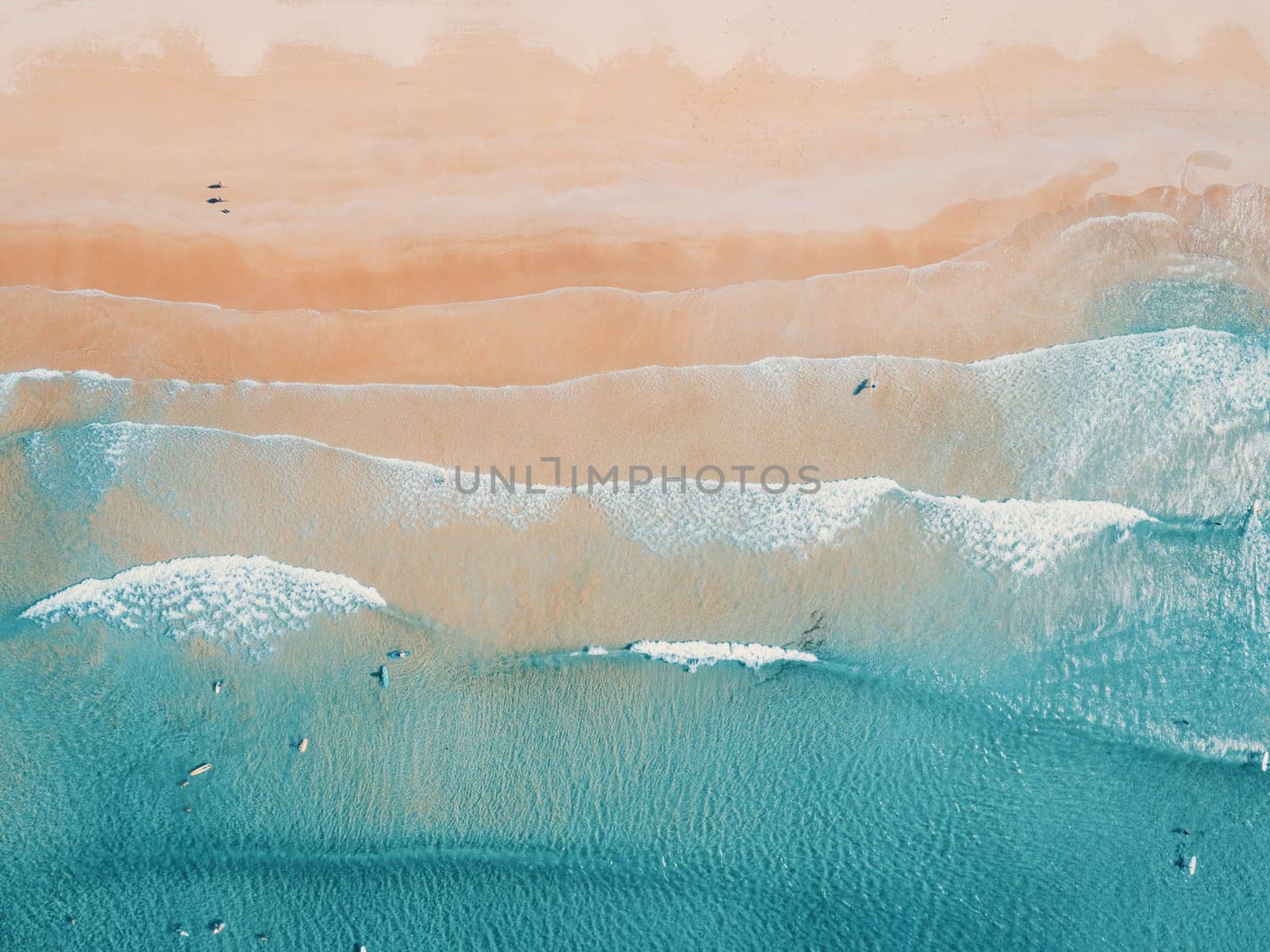 Aerial top view of turquoise ocean wave reaching the coastline.