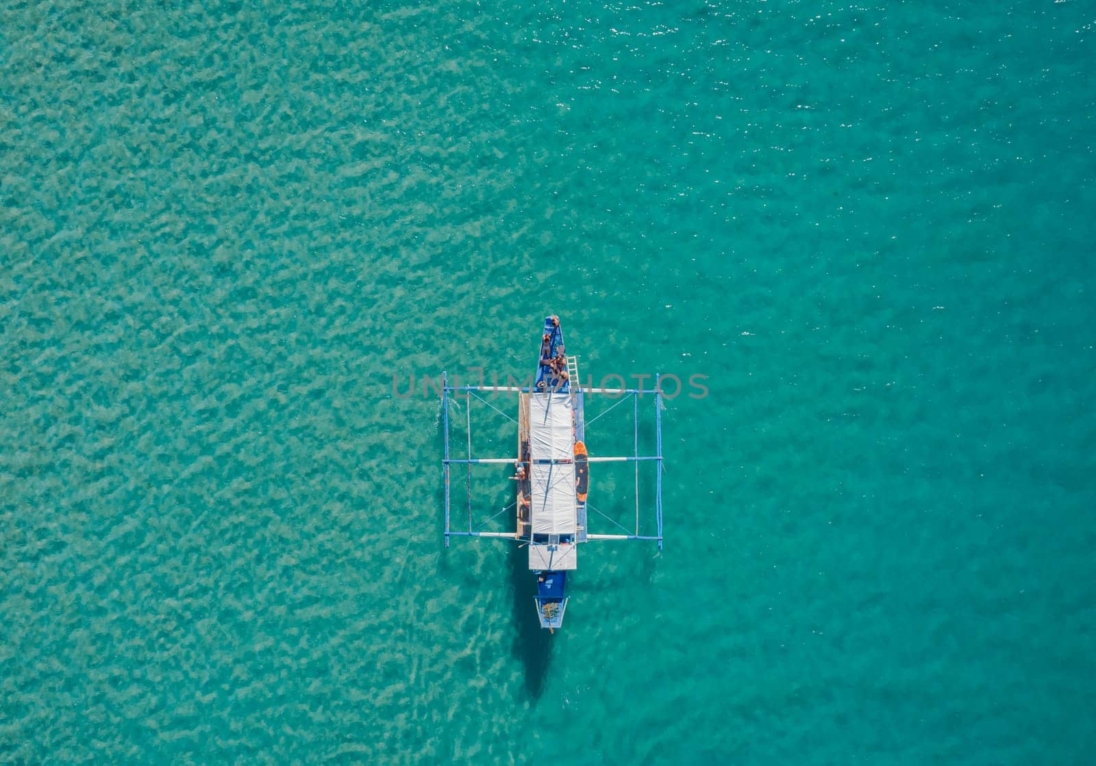 Aerial drone view of boat anchored in the bay with clear and turquoise water on sunny day. Boat in the tropical lagoon. by Busker
