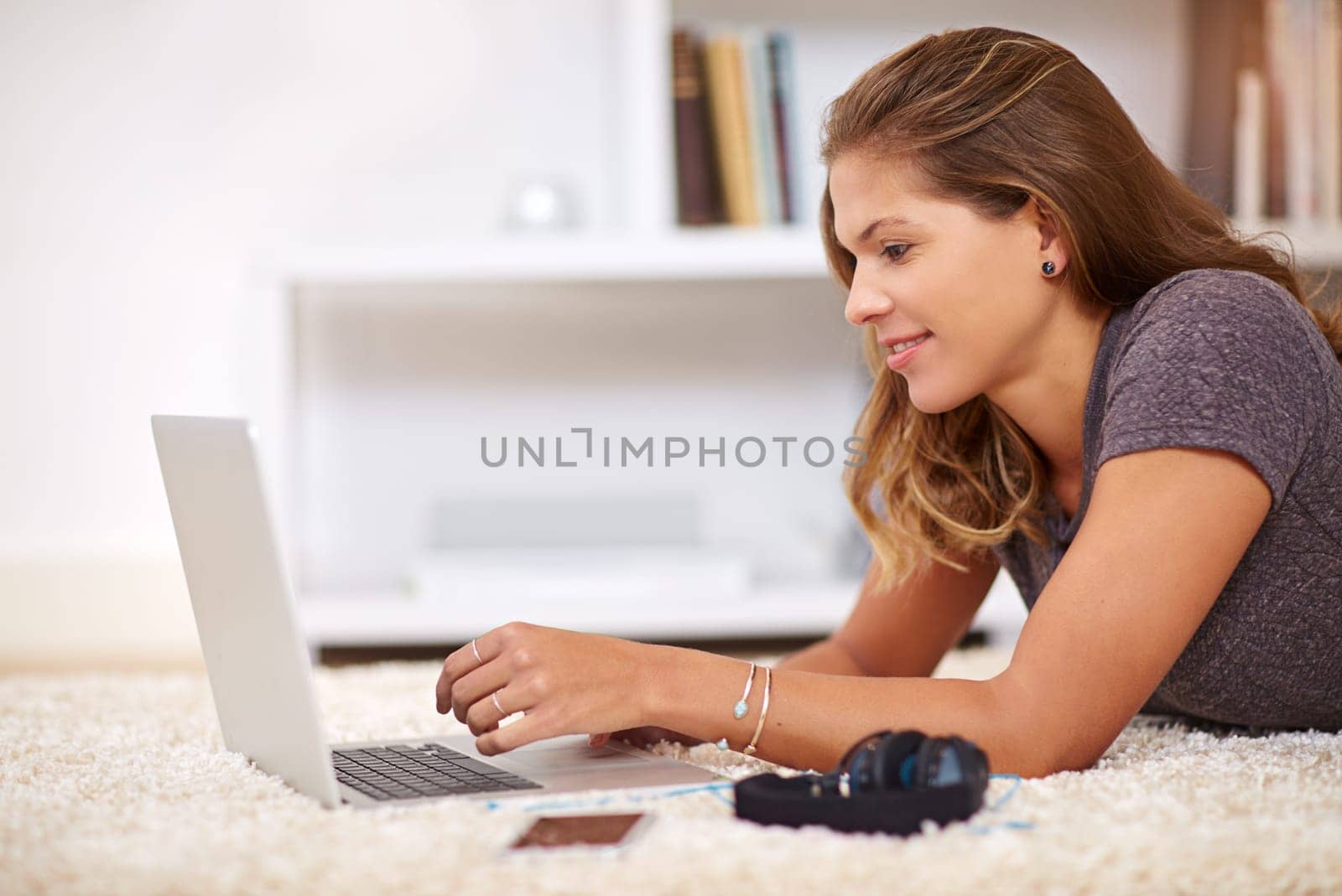 Woman, laptop floor and home for student, education and elearning for online research. Typing, relax and study with computer for project or assignment, female person and swim for calm in house lounge by YuriArcurs