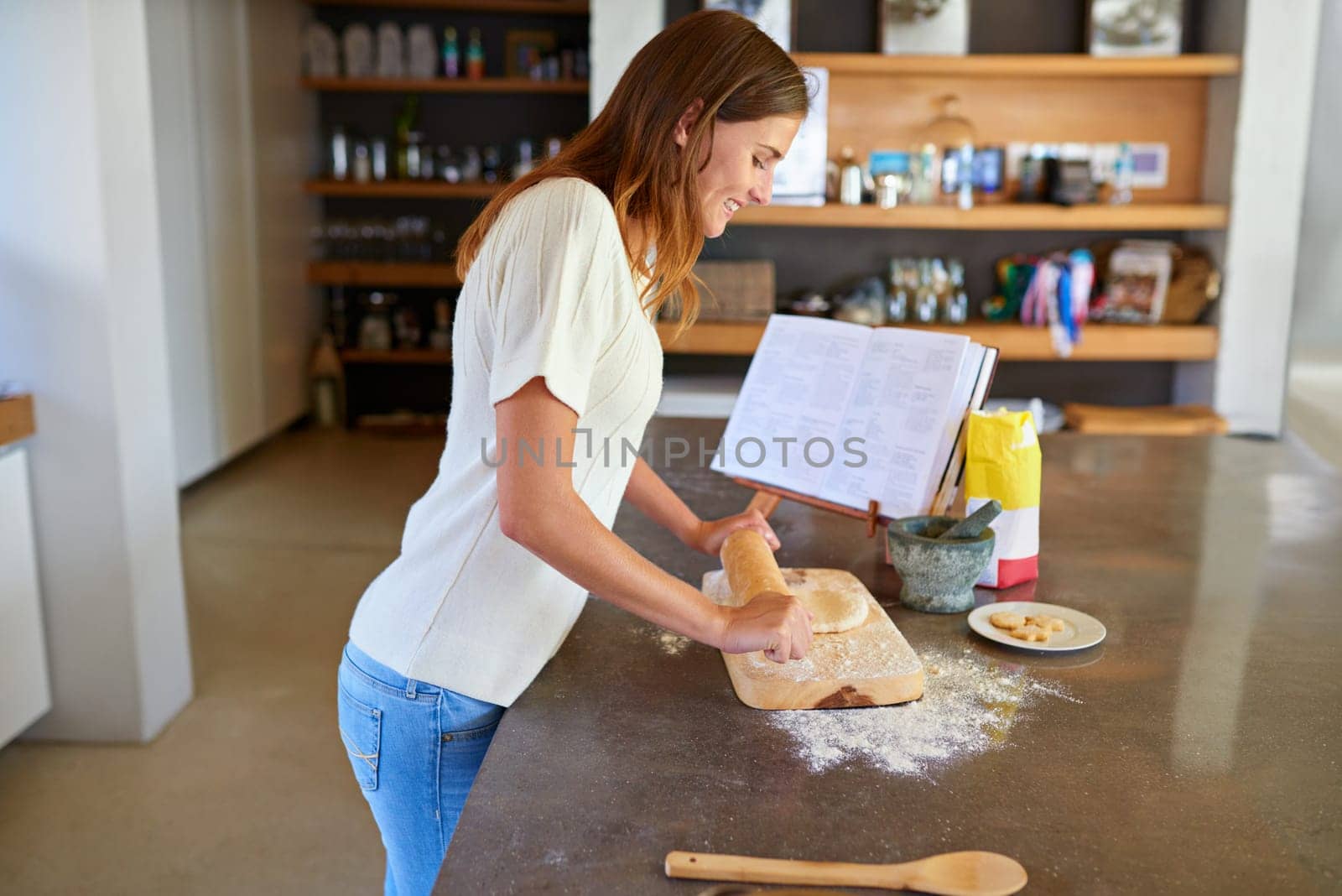 Baking, home and woman with recipe, book and smile for lunch with flour, dough and rolling pin. Diet, wellness and happy female person in kitchen with ingredients, nutrition or healthy homemade bread by YuriArcurs