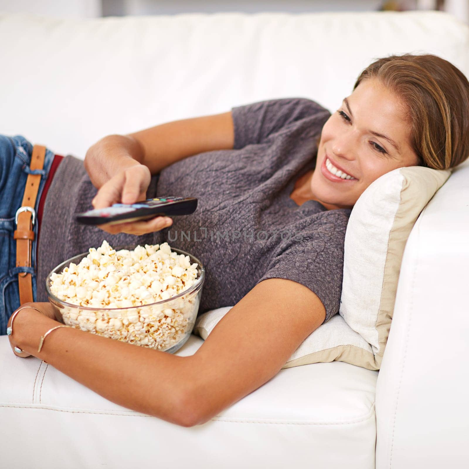 Woman, sofa and food with remote and relax in home, popcorn and watching on weekend. Holiday, entertainment and break with movie or show, streaming or living room on couch for vacation and self care.