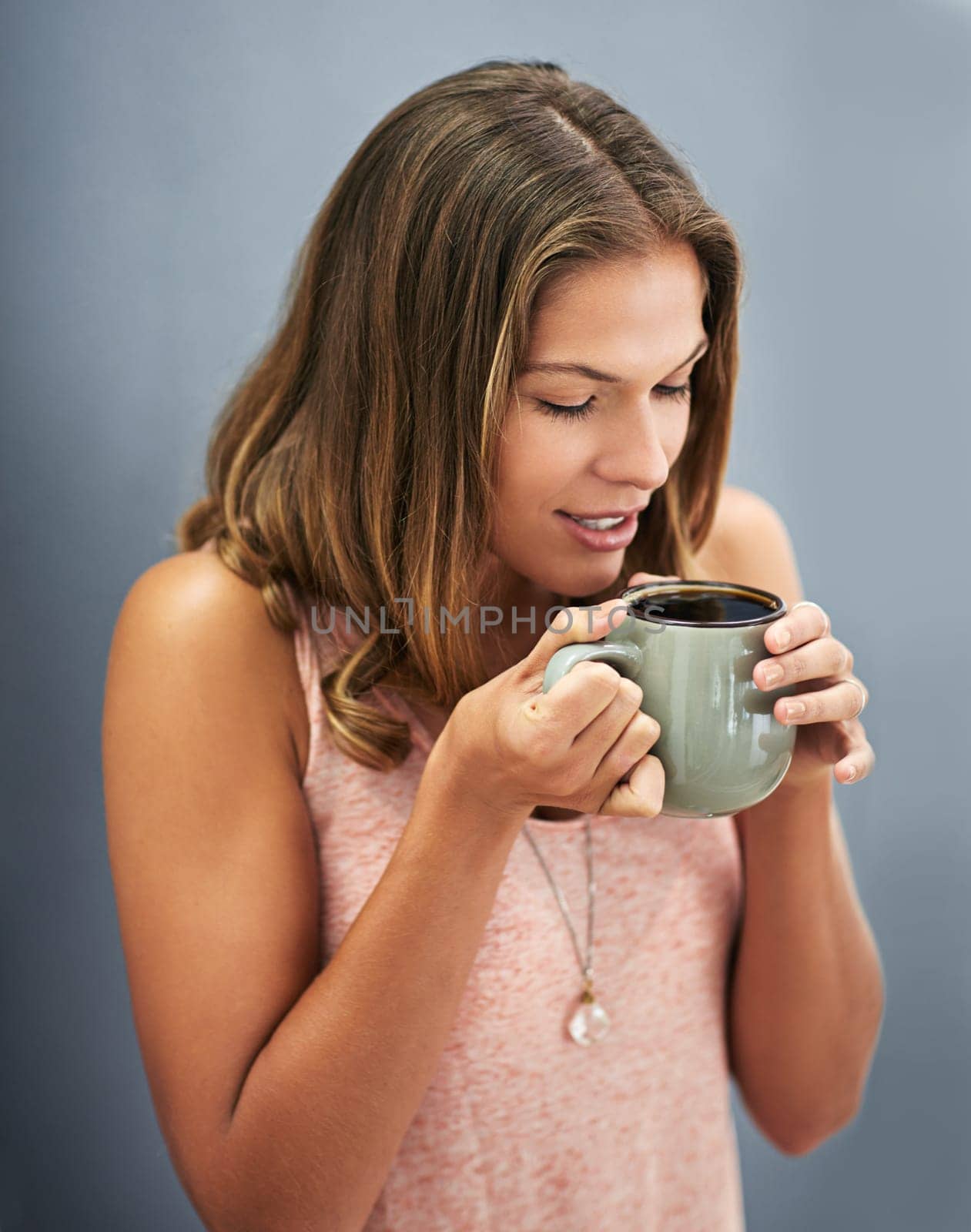 Smile, coffee and woman in studio for happiness, break and calm morning on gray background. Mug, cappuccino and female person drinking hot beverage for relax, peace or to start day on dark backdrop.