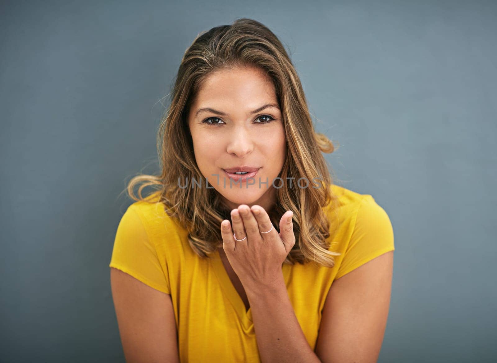Woman, blowing a kiss and portrait with studio, love and smile for romance isolated on grey background. Model, hand and gesture for affection, flirt and emoji for valentines care and happiness.