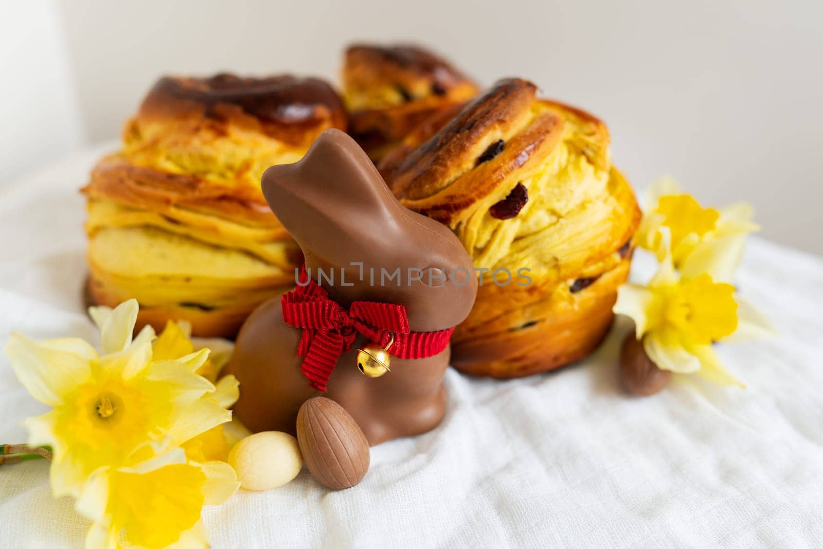 Homemade Easter traditional pastries lie on a green napkin along with daffodil flowers, rabbit, chocolate eggs. Easter baking and decoration