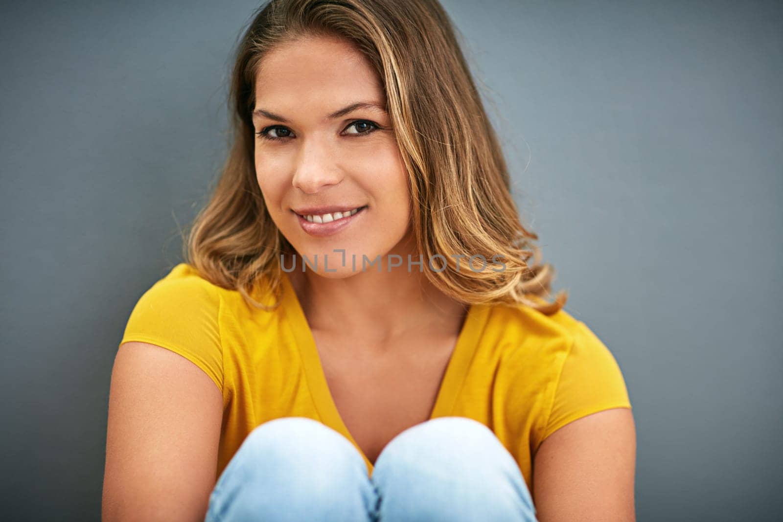 Woman, portrait and sitting on ground by studio background with smile, yellow and mockup for marketing. Happy, confidence and face of gen z model by dark backdrop with color and space for advertising.