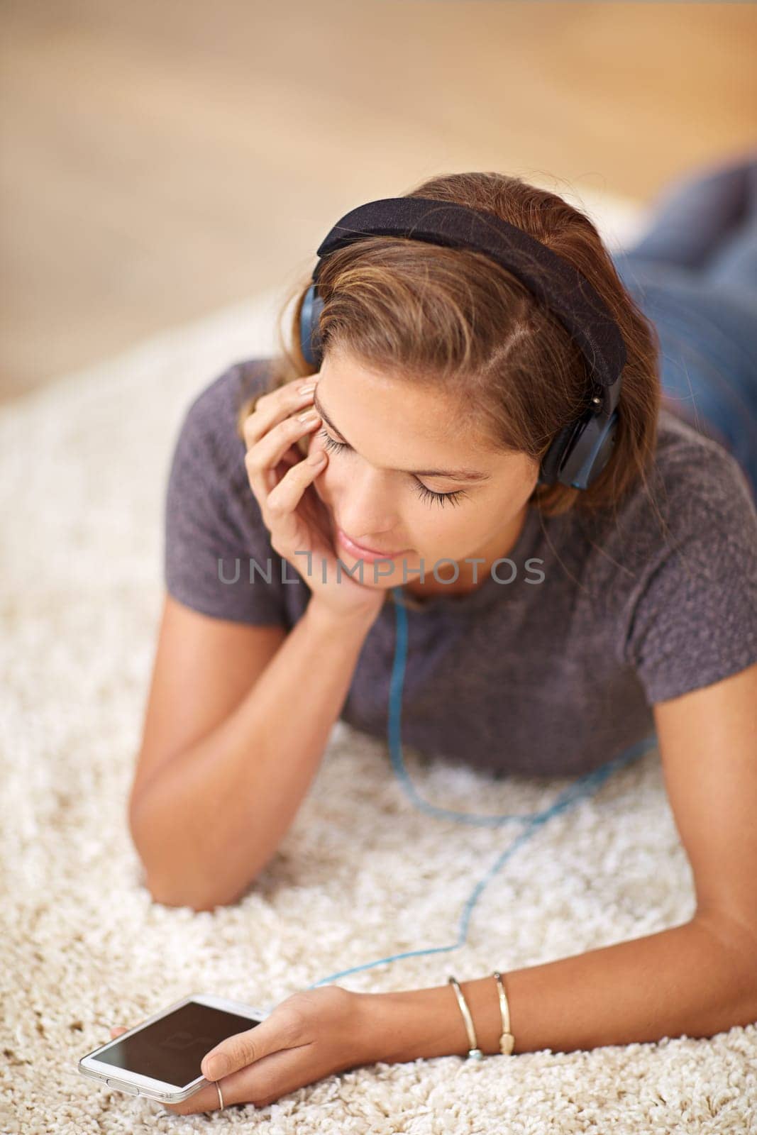 Carpet, headphones or woman with phone for music streaming, subscription or wellness in home. Smile, girl or female person listening to audio, track or song to relax on floor on mobile app for peace.