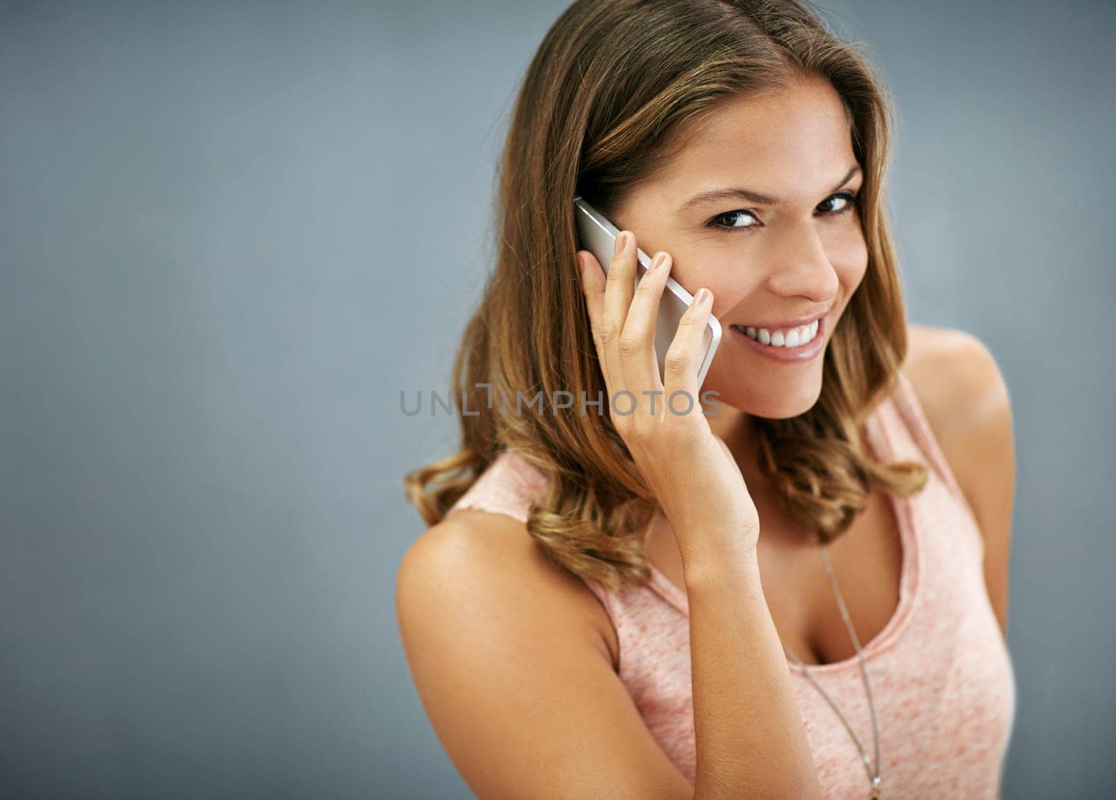 Face, phone call and happy woman talking in studio for story, gossip or news discussion isolated on a gray background. Mobile, smile or portrait of model in conversation, chat or listening on mockup.