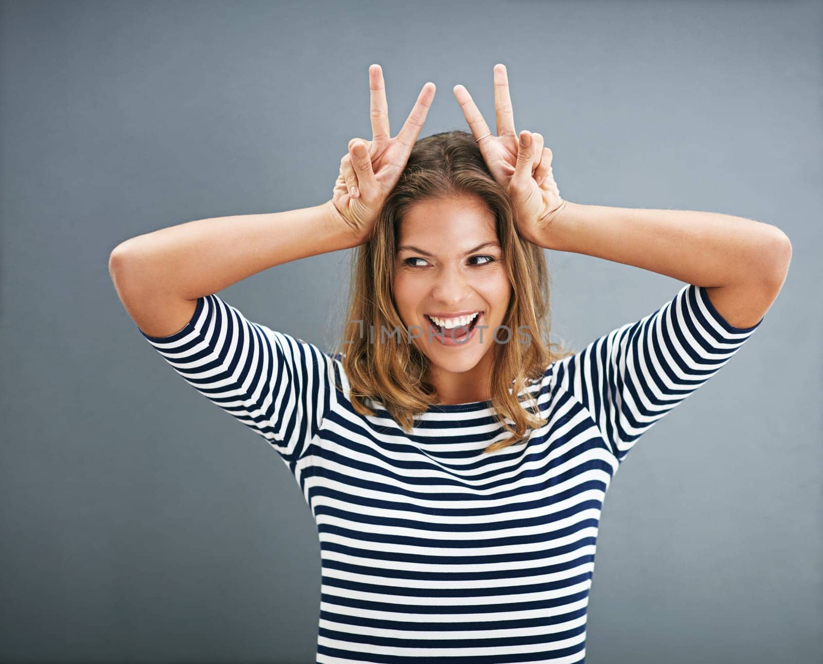 Woman, bunny ears and fingers in studio for funny joke, happy and play on gray background. Female person, emoji and rabbit icon or symbol for comedy, comic gesture and mockup space for easter humor.
