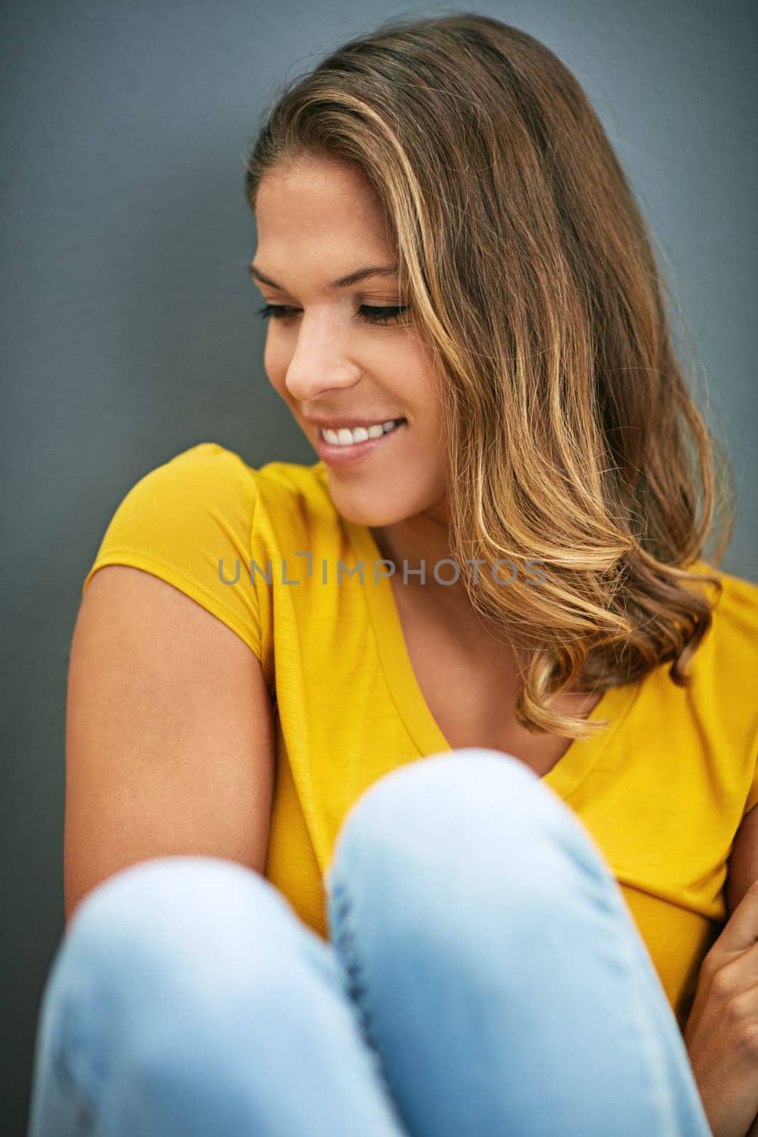 Wall, weekend and woman on floor, rest and relax for with smile, Gen z and streetwear for fashion in house. Grey background, happiness and girl in apartment, cheerful and comfortable on ground.