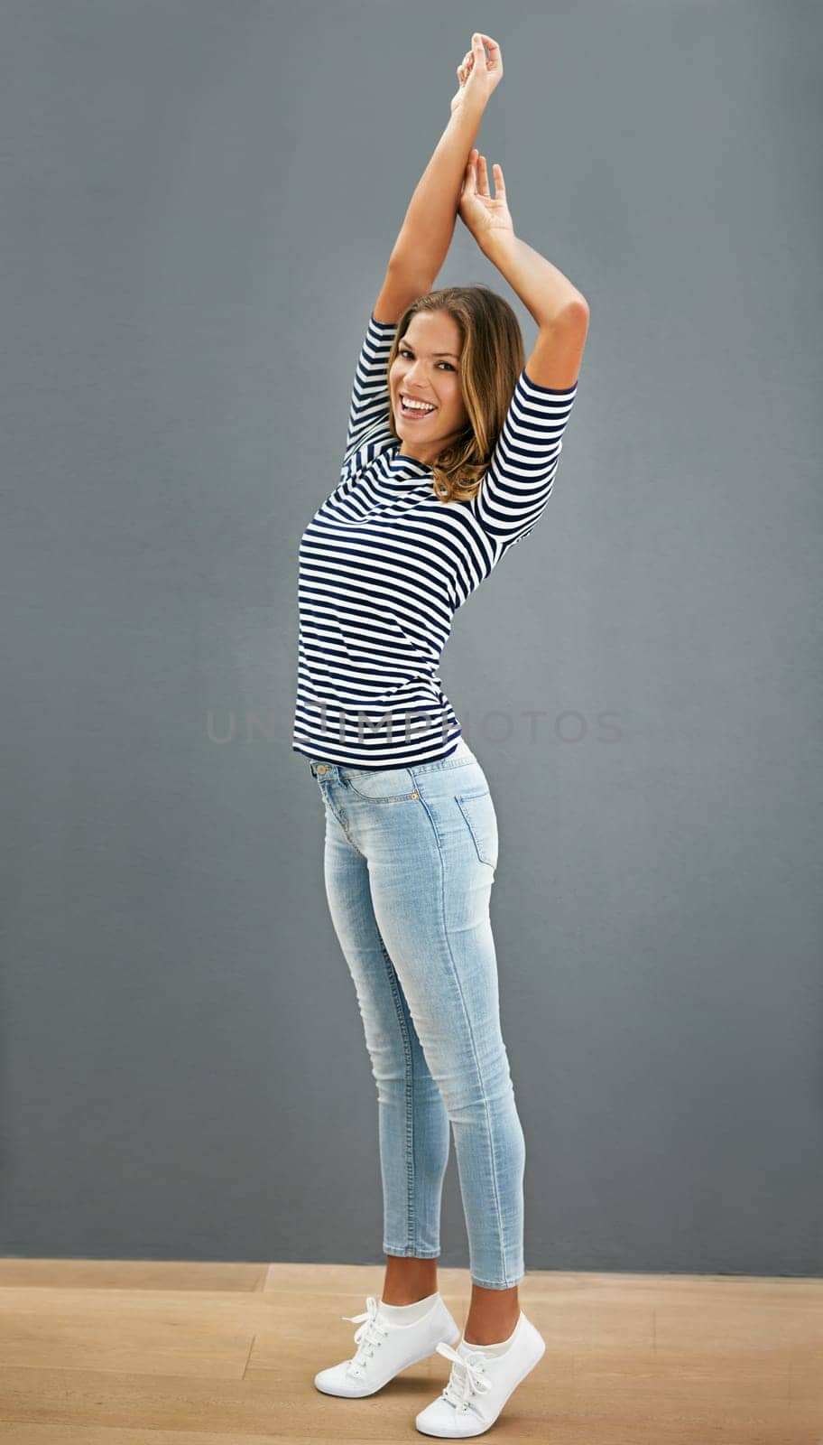 Woman, happy and home fashion or relaxing, casual and carefree or stretch for portrait. Standing, grey wall and smiling in denim jeans with confident girl, weekend and comfort style or outfit.