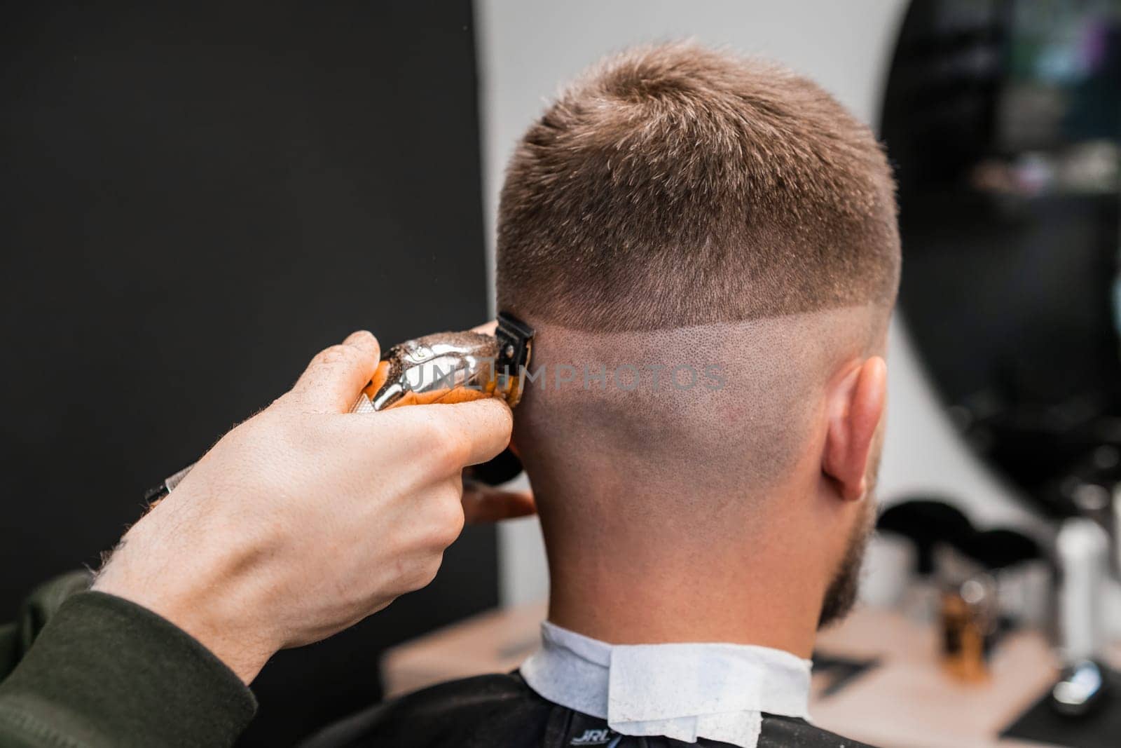 Hairstylist shaves male occiput with trimmer in barbershop by vladimka